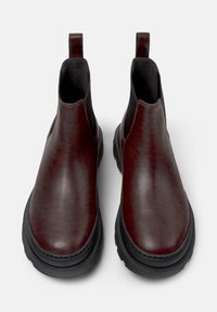 Stivali Chelsea in pelle bordeaux con pannelli elastici laterali, linguette e suole in gomma nera. Texture liscia con una leggera lucentezza.