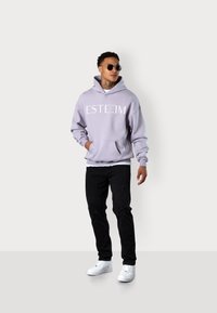 Lavender hoodie with "ESTEEM" logo, kangaroo pocket, and ribbed cuffs; paired with black distressed jeans and white sneakers.