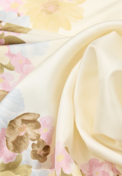 Ύφασμα σε εκρού χρώμα με παστέλ λουλουδάτο μοτίβο που περιλαμβάνει κίτρινα, ροζ, μπλε και καφέ λουλούδια, εμφανιζόμενο με απαλές πτυχώσεις και ομαλή υφή.