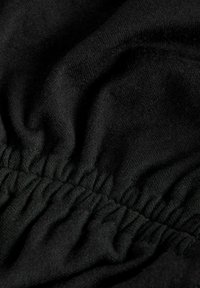 Must Black fabric with a soft texture, featuring gathered stitching along a seam. The material appears stretchy and tightly woven.