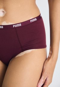 Bordové bavlnené hipster nohavičky s bielym logom Puma na páse. Má bezšvový dizajn a jemnú, elastickú látku.