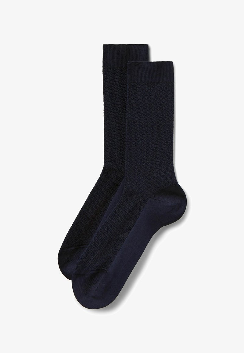 Paire de chaussettes bleu marine foncé à motifs, longueur mi-mollet, avec talons et bordures renforcés, posées à plat sur un fond blanc.