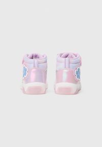 Tênis mid-top em roxo e rosa, com tecido em malha, detalhes iridescentes, um acabamento em flor na lateral e um colarinho acolchoado para conforto.