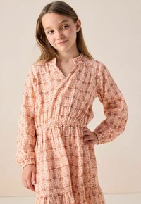 Blumenmuster-Kleid in sanften Pfirsichtönen, mit elastischer Taille, langen Ärmeln und einem V-Ausschnitt mit volantiertem Kragen. Leichtes Material.