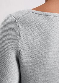 Jasnoszara sweter dziany z teksturowanej tkaniny, okrągłym dekoltem i wszytymi ramionami, podkreślający minimalistyczny design.