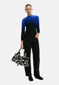 Top de manga larga con degradado de azul a negro y patrón de zigzag texturizado, combinado con pantalones anchos negros y un bolso en blanco y negro con acentos gráficos.
