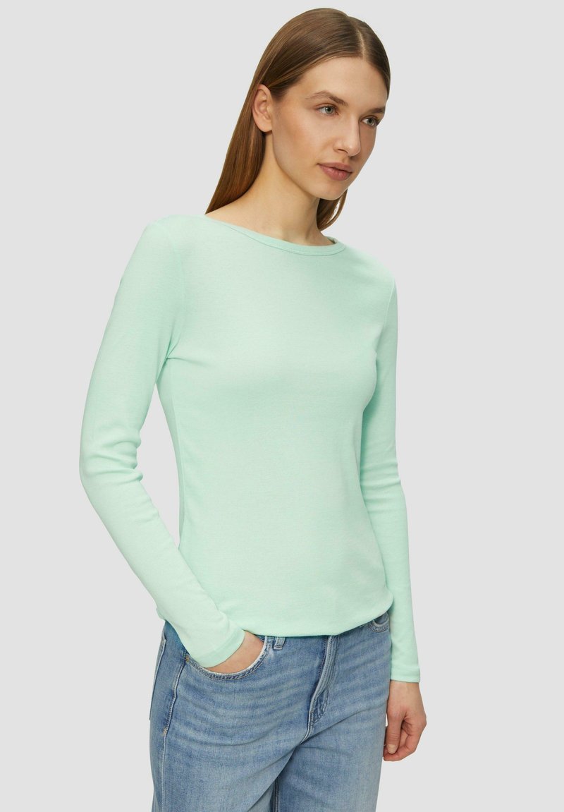 Lange mouwen mintgroen shirt van zacht materiaal met een ronde halslijn, gecombineerd met lichtblauwe jeans. Aansluitend ontwerp, minimale details.