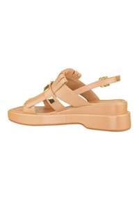 Sandal beige realizzata in pelle liscia, con una suola a zeppa bassa, punta aperta, cinturini incrociati e dettagli in tono dorato, dotata di cinturini per il tallone regolabili.