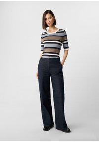 Gestreiftes Strickoberteil in Braun, Blau und Weiß mit kurzen Ärmeln. Kombiniert mit dunkelblauen, weiten Hosen. Glatte Textur, neutrale Farben.
