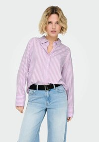 Chemise rose clair à rayures avec un col et des manches longues, associée à un jean bleu à jambes larges et une ceinture noire.