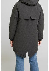 Parka larga gris oscuro con capucha, que presenta una abertura en la parte posterior y puños elásticos. El material parece suave con un acabado texturizado.