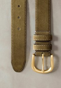 Cintura in suede verde oliva con fibbia in metallo dorato, caratterizzata da dettagli di cucitura e molteplici fori di regolazione per flessibilità di misura.