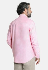 Camisa de manga larga abotonada en rosa claro con un patrón texturizado sutil; presenta un cuello y puños abotonados. Se muestra la vista posterior.