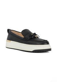 Black leather slip-on shoe with a rounded toe, featuring a decorative bow, subtle gold accents, and a thick white platform sole.