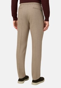 Beige kalhoty s dobře střiženým střihem, elastickým pasem a dvěma zadními kapsami; v kombinaci s tmavými slip-on botami a vínovým svetr.