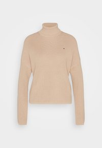 Beżowy, prążkowany sweter z golfem, z długimi rękawami i małym, prostokątnym logo na lewej piersi.