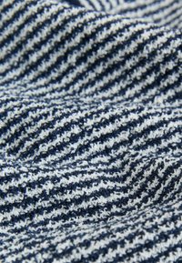 Tissu rayé marine et blanc avec une surface texturée, présentant un motif doux en tricot bouclé, étroitement tissé avec des couleurs alternées.