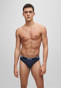 Herrenunterwäsche in Marineblau mit einem weißen "BOSS"-Logo am Bund, aus einem glatten Stoff gefertigt und in einem klassischen Slip-Schnitt.