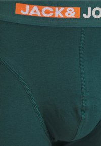 Teal herenboxershorts met een elastische tailleband waarop "JACK & JONES" in wit en oranje is afgebeeld. Glad materiaal en platte naden voor comfort.