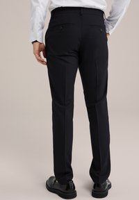 Svarta kostymbyxor med skräddarsydd passform, som har två bakfickor med knappar, slät textur och pressade ben för ett sofistikerat utseende.