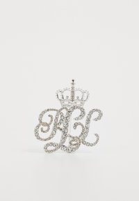 Rhinestone brosje med et stilisert monogramdesign og en krone detalj over. Metallisk sølvfarge med en glitrende finish.