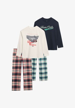 Due magliette a maniche lunghe: una color crema con una grafica di baseball, l'altra blu navy con il testo "Team Chill". Pantaloni a quadri intrecciati in rosso/nero e verde/bianco.