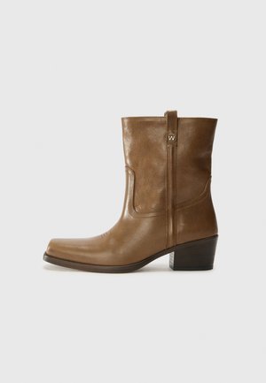 Brown leather ankle boot with a square toe, textured finish, and a low stacked heel. Features a rear pull tab and subtle stitching details.