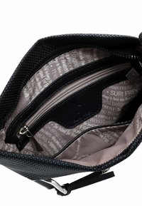 Interno di una borsa nera con un materiale texturizzato. Presenta una tasca con zip e una fodera con motivi testuali ripetuti in grigio chiaro.