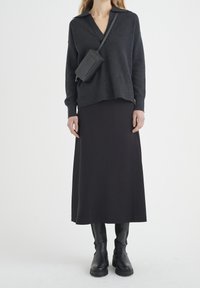 Tmavě šedý pletený svetr s véčkovým výstřihem a spadlými rukávy, kombinovaný s dlouhou černou sukní a černými kozačkami po kolena. Součástí je i přes rameno nošená taška.