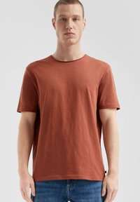 Roodkleurig katoenen t-shirt met ronde hals, korte mouwen en een relaxte pasvorm. Glad textuur met minimale patronen en een zijlabel detail.