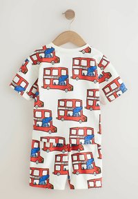 Kortärmad pyjamasuppsättning med en vit bakgrund som har ett upprepat mönster av röda dubbeldäckare och blåa tecknade alligatorer.