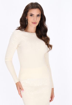 Maglione a coste di colore crema chiaro con maniche lunghe, caratterizzato da decorazioni di paillettes sparse nella parte superiore, che si fondono delicatamente con una sezione inferiore semplice.