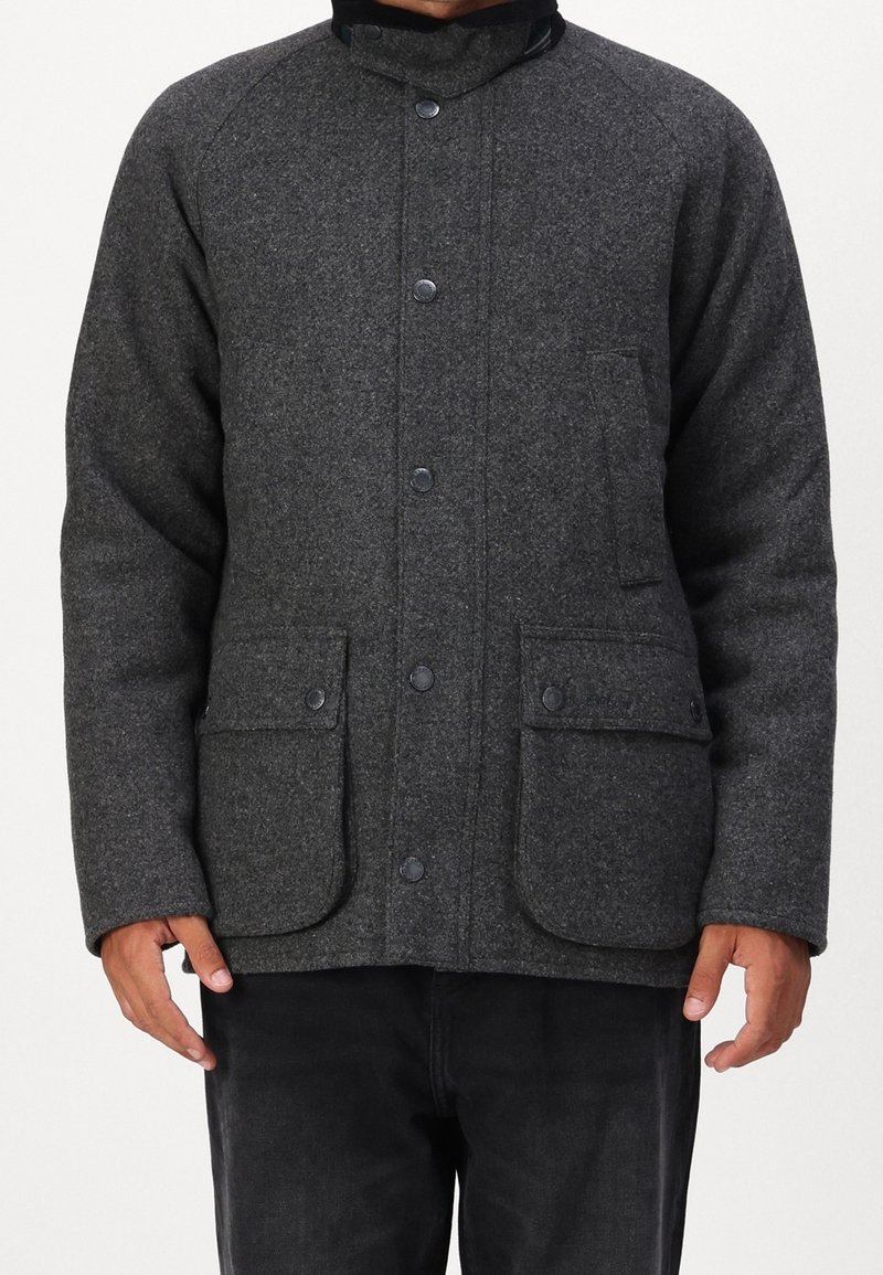 Grijs jack van een wolmix met een hoge kraag, drukknoopsluitingen aan de voorkant, twee grote voorzakken en een textuurrijke oppervlakte.