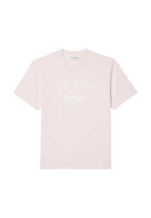 T-shirt en coton rose avec un col rond, des manches courtes et un logo crocodile blanc avec le texte "LACOSTE PARIS" dans un design incurvé.