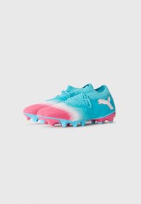 Des crampons de football dégradés bleu et rose avec des lacets et un logo Puma blanc, positionnés côte à côte sur un fond blanc.