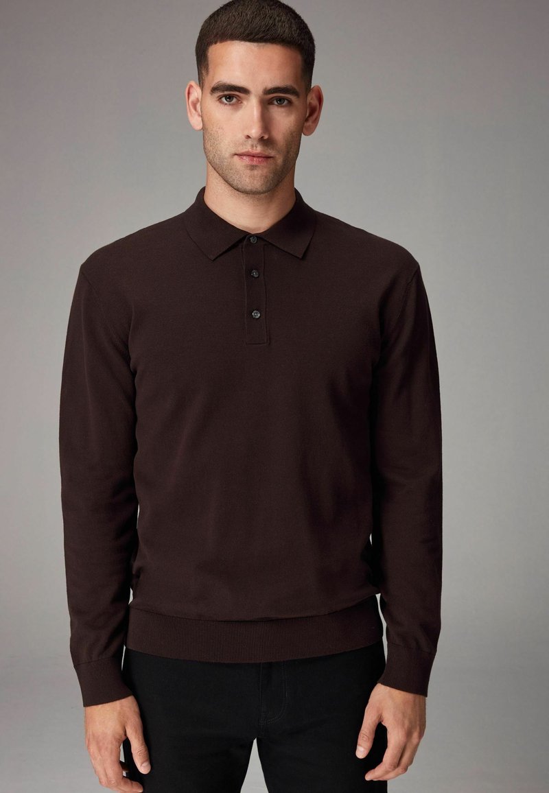 Dunkelbraunes langärmliges Poloshirt mit Kragen und einer Drei-Knopf-Leiste. Rippbündchen und Saum sorgen für eine figurbetonte Optik.