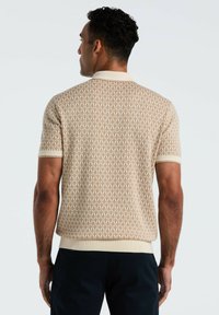 Beige polo shirt met korte mouwen, voorzien van een herhalend patroon, geribde kraag en boorden, en een geweven structuurafwerking.