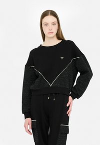 Zwarte sweatshirt met textuur en glanzende mouwen en een contrasterend driehoekontwerp. Heeft een ronde halslijn en een aansluitende manchet.