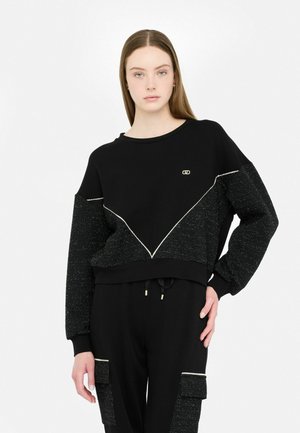 Felpa nera con maniche testurizzate e lucide e un design a triangolo contrastante. Presenta un collo rotondo e polsini aderenti.