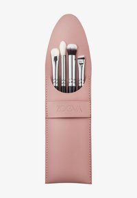 Porta pennelli in pelle rosa con quattro pennelli per trucco. I pennelli presentano ferule argentate e diverse forme e texture delle teste.
