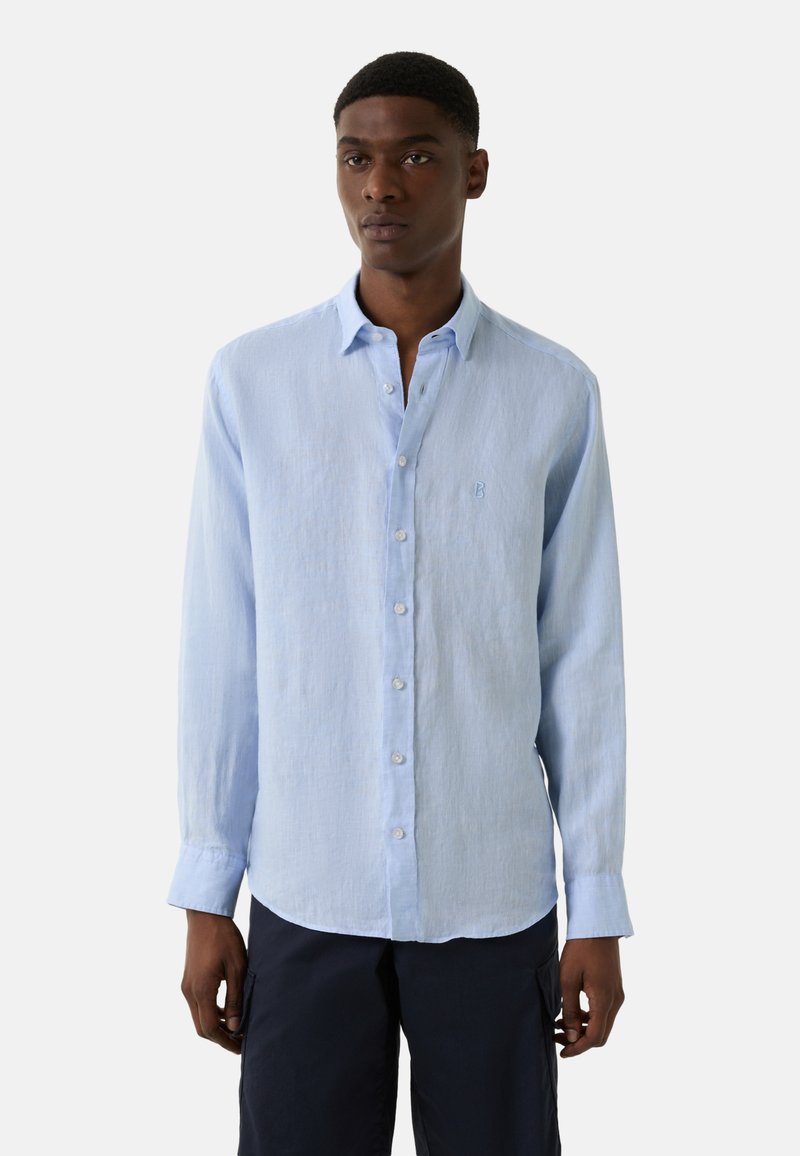 Lichtblauwe blouse met lange mouwen van linnen, voorzien van een button-down kraag, witte knopen en een geborduurd logo op de borst. Zachte textuur en een ontspannen pasvorm.