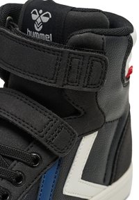 Svart högskodd sneakers som har en kombination av läder och mocka, med en vit zigzagdesign, svarta snören och kardborreband.