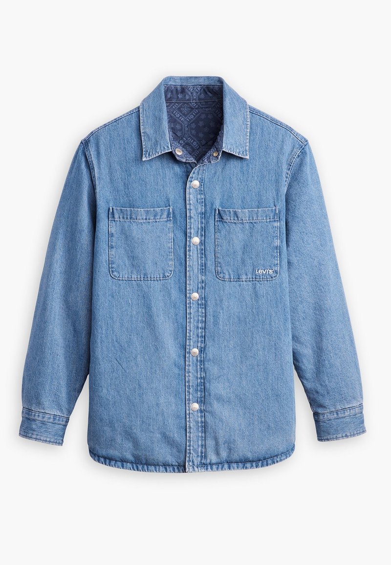 Camisa de denim de color azul claro, con cierre de botones en la parte delantera, dos bolsillos en el pecho y un forro interior de color azul oscuro con un patrón. Incluye un cuello.