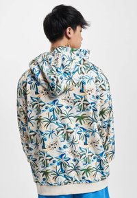 Sudadera con capucha de color beige claro, con un estampado de palmeras en azul y verde, textura suave y puños y dobladillo de canalé.