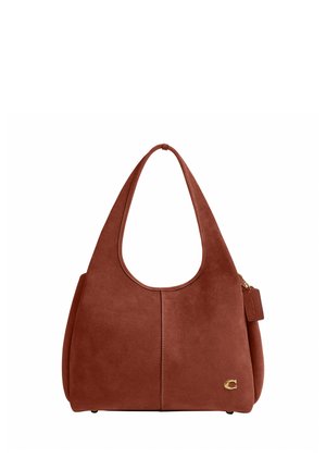 Sac à main en daim marron avec des anses larges, une couture discrète au centre, un petit logo doré en bas à droite et une étiquette en cuir suspendue sur le côté.