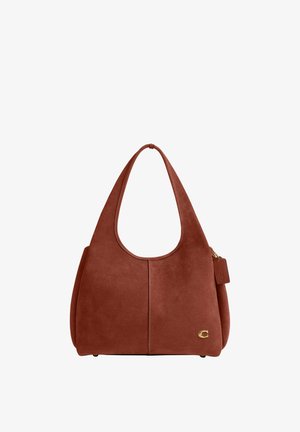 Sac à main en daim marron avec des anses larges, une couture discrète au centre, un petit logo doré en bas à droite et une étiquette en cuir suspendue sur le côté.