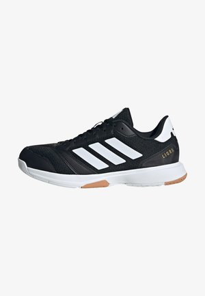 Scarpa sportiva nera con tomaia texturizzata, design a tre strisce bianche, suola bianca e un piccolo accento dorato sul tallone.