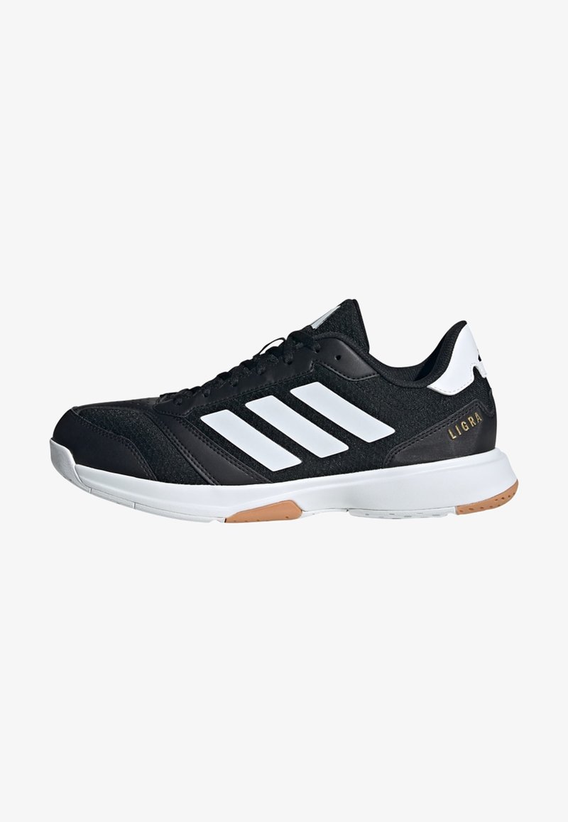 Zapatilla deportiva negra con un upper texturizado, diseño de tres franjas blancas, suela blanca y un pequeño acento dorado en el talón.