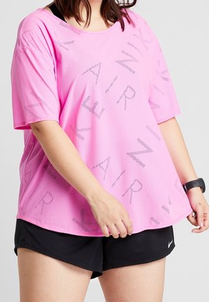 Kvinde iført en løs lyserød Nike Air mesh t-shirt, sorte atletikshorts og et sort fitnessur på håndleddet.