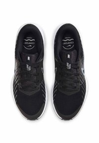 Baskets de sport noires avec une tige en mesh, semelle blanche et accents gris. Présentent une pointe ronde et un système de laçage pour un ajustement sécurisé.